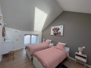 twee bedden in een zolderkamer met roze lakens bij Le Gîte du Pèlerin avec piscine in Florennes +13 foto's