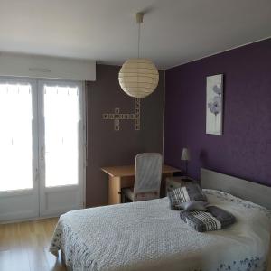 ein Schlafzimmer mit einem Bett mit einer lila Wand in der Unterkunft Les flots bleus face à la mer in Notre-Dame-de-Monts