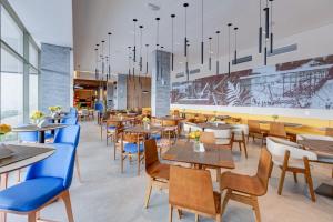 カラグアタトゥーバにあるHampton By Hilton Caraguatatuba Serramarの木製のテーブルと青い椅子のあるレストラン