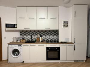 a kitchen with white cabinets and a washer and dryer at Light One Bed Flat next to the Ski Lift in Bansko