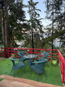 a table and chairs on a deck with a red fence at Ufo Mussoorie in Mussoorie
