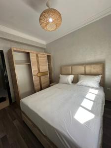 une chambre avec un grand lit avec des draps blancs dans l'établissement Ocean Escape 5 min tgv, à Tanger