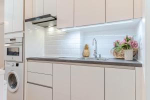 a white kitchen with a sink and a dishwasher at Apartamento Abenhamar in Granada +7 photos