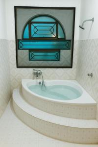 PūrnānkuppamCeleste Luxury Bungalow的一间带彩色玻璃窗的浴缸的浴室