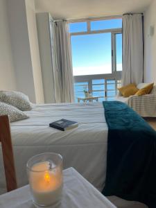 a candle on a bed with a view of the ocean at &luxe vista mar& in Calpe