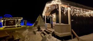 a house covered in christmas lights in the snow at Liten gårdshytte til leie in Åseral +8 photos