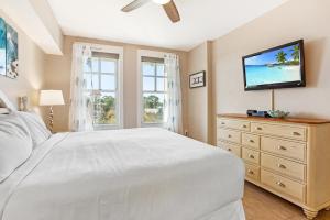 a bedroom with a white bed and a dresser with a flat screen tv at Observation Point North 456 in Destin