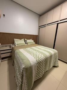 a bedroom with a bed with a green and white blanket at Casa no Jardim Abrel in Santa Inês