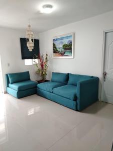 a living room with two blue couches and a chandelier at Mi refugio cerca del aeropuerto in Santo Domingo