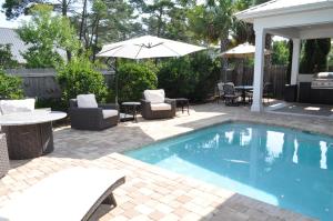 einen Pool mit Stühlen, einem Tisch und einem Sonnenschirm in der Unterkunft Oceans 11 Oasis at Gulf Place in Santa Rosa Beach