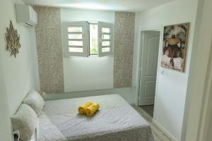 a yellow stuffed animal sitting on a bed in a room at Milo Cosy T2 climatisé à 2 mn de la plage du 972 in Sainte-Luce