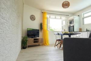 a kitchen and living room with a television and a table at Milo Cosy T2 climatisé à 2 mn de la plage du 972 in Sainte-Luce