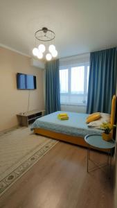 a bedroom with a large bed with blue curtains at New апартаменты возле Материнства и Детства in Taldykolʼ