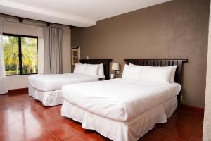 a hotel room with two beds and a window at Ancestral Copan in Copan Ruinas
