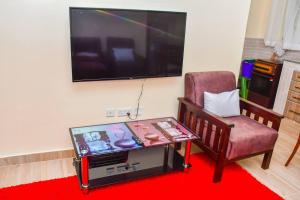 - un salon avec une télévision, une table et une chaise dans l'établissement Garden lodge near Ngong with forest walks - 2340, à Kiserian
