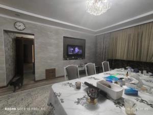 a dining room with a table and a tv on a wall at Екохостел in Bishkek