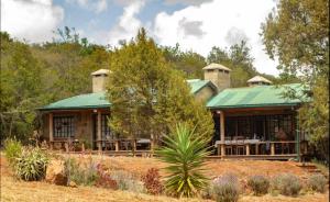 a house with a green roof in a field at Laikipia farmstay Chui Cottage near Nanyuki - 2330 in Timau