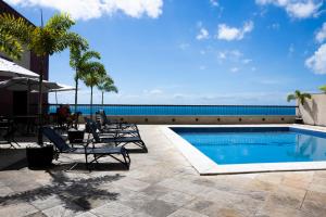 a swimming pool with lounge chairs and the ocean at Studio-Apartment Center Pool Free Parking in Salvador
