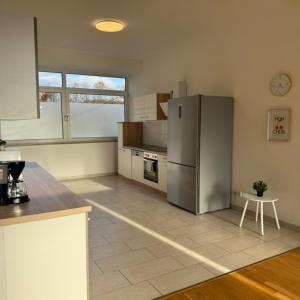 eine Küche mit einem Kühlschrank aus Edelstahl und einem Tisch in der Unterkunft T&K Apartments - Comfortable 4 and 5 room Apartments - 20min Fair Messe CGN in Overath