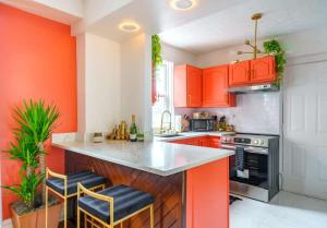a kitchen with orange cabinets and a counter with stools at Jungle House Luxury Homes - Columbus Downtown Short North - Steps to Convention Center & Nationwide Arena - Sleeps up to 8 - Free Parking - Over 5,800 Five Stars in Columbus