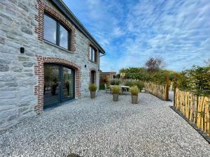 een stenen huis met een patio met potplanten bij Le Gîte du Pèlerin avec piscine in Florennes