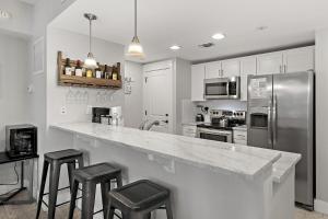 a kitchen with a counter with stools and a refrigerator at Pilot House 413 in Destin