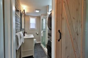 a bathroom with a sink and a toilet and a door at Classic Killington Ski Chalet for 8 with Gear Room, 2 Fireplaces, 5 Mins to Slopes in The Woods +24 photos