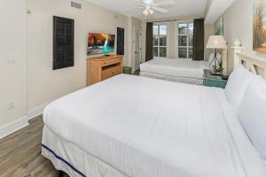 a white bedroom with two beds and a window at Pilot House 507 in Destin