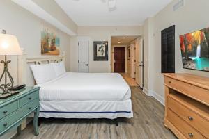 a bedroom with a white bed and a blue dresser at Pilot House 507 in Destin