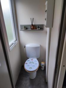 ein kleines Badezimmer mit Toilette und Fenster in der Unterkunft Mobilhome cosy, spacieux au bord de l'Eure in Ivry-la-Bataille + 9 Fotos