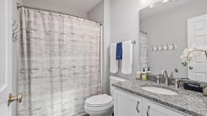 a white bathroom with a shower curtain and a toilet at Downtown Condo - 2BR 2BA Walk to Everything in Raleigh