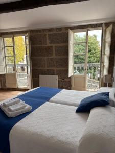 a bedroom with a large white bed with blue pillows at Pension Via-Stella in Santiago de Compostela