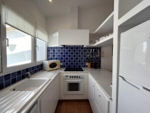 a white kitchen with a sink and a stove at Riera Rossello 1 in Fornells +28 photos