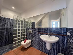 a blue tiled bathroom with a sink and a toilet at Riera Rossello 1 by SOM Menorca in Fornells +14 photos