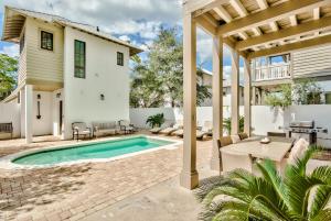 un patio con piscina e una casa di Rolling Dunes a Inlet Beach