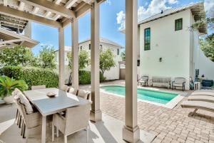 un patio con tavolo e sedie accanto alla piscina di Rolling Dunes a Inlet Beach