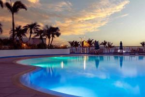 a swimming pool with palm trees and a sunset at Royal Islander Club Resort La Terrasse in Lowlands