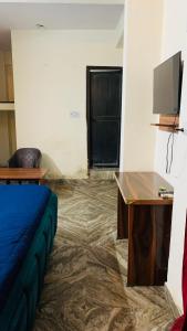 a room with a bed and a desk and a tv at Glory hotel in Noida