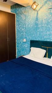 a blue room with a bed and a blue wall at Glory hotel in Noida