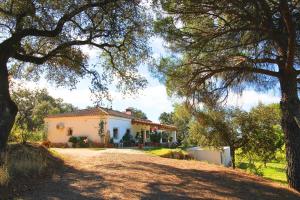 a white house with a tree in front of it at Casa Rural El Membrillo by SIERRA VIVA in Jabuguillo
