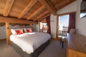 a bedroom with a bed and a desk and a window at Le Flocon d'Argent in Les Gets