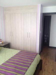 a bedroom with a bed with white cabinets and a striped rug at Hospedaje en Quito Sectro Financiero in Quito