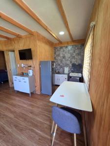 a kitchen with a table and two chairs and a refrigerator at Cabaña Playa Chauquen in Neltume