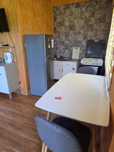 a kitchen with a white table and a refrigerator at Cabaña Playa Chauquen in Neltume +7 photos
