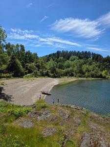 a group of people standing on a beach next to a lake at Cabaña Playa Chauquen in Neltume