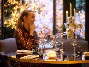 巴黎索菲特巴黎法布格酒店的坐在桌子上戴酒杯的女人