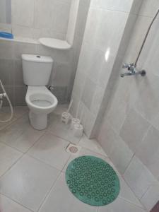 La salle de bains est pourvue de toilettes et d'une douche avec un tapis vert. dans l'établissement Ensuite rooms in a furnished apartment in Tudor, Mombasa TF1, à Mombasa