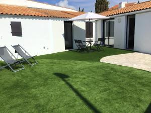 ein Garten mit Gartenstühlen und einem Haus in der Unterkunft Face à la plage in Rivedoux-Plage + 8 Fotos