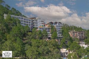 een appartementengebouw op een heuvel met bomen bij The BlackPearl Hillcrest in Kasauli