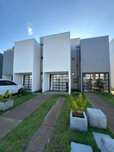 a white building with a car parked in front of it at Refúgio Amazônico com Piscina e Natureza in Manaus